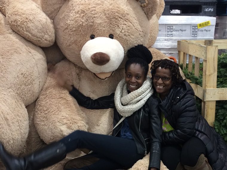 Our family laughing beside giant teddy bears, with holiday wreaths nearby